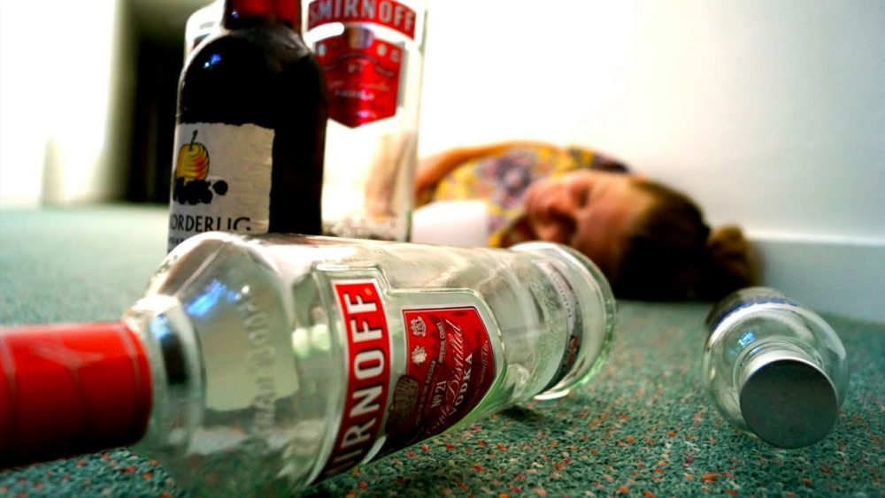 Девушка лежит на полу рядом с бутылками