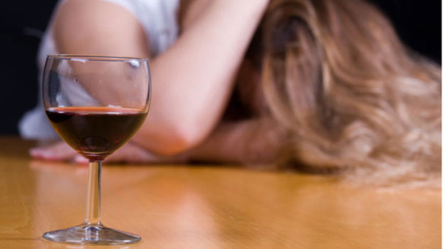 Девушка сидит рядом с бокалом вина