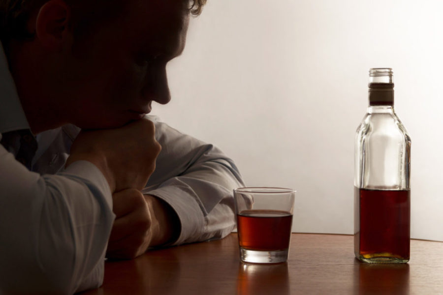 Мужчина смотрит на стакан со спиртным