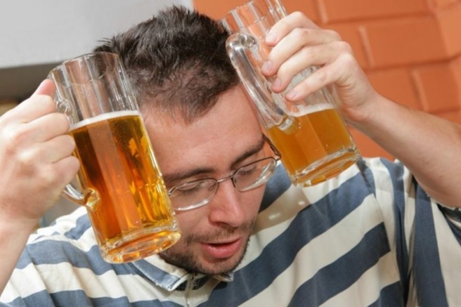 Мужчина держит бокалы с пивом у головы