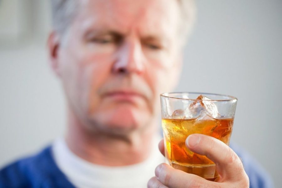 Мужчина держит стакан с алкоголем