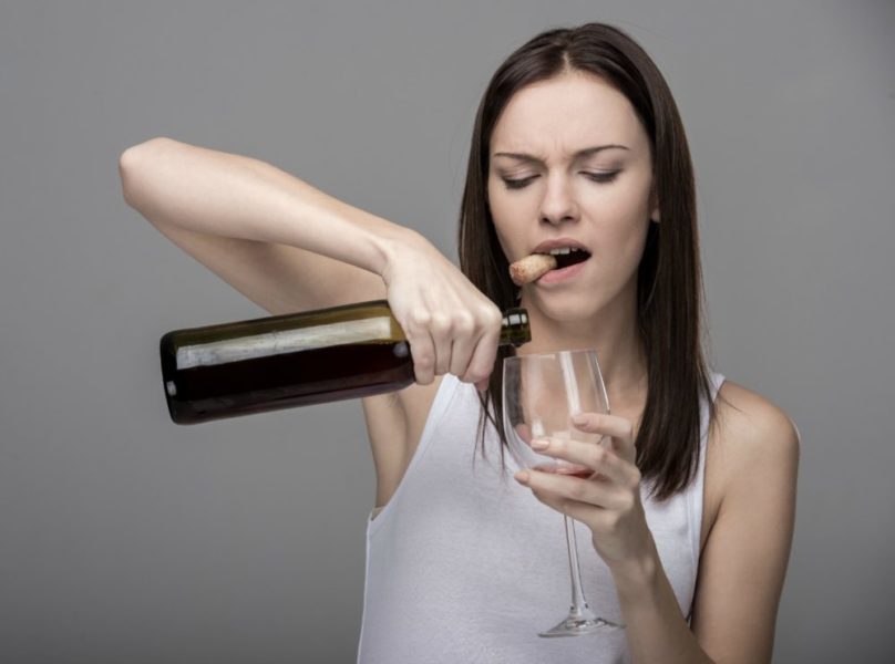 Девушка наливает себе вино