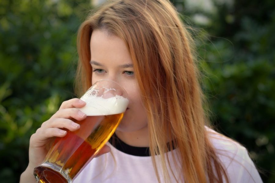 Девушка пьет пиво из бокала